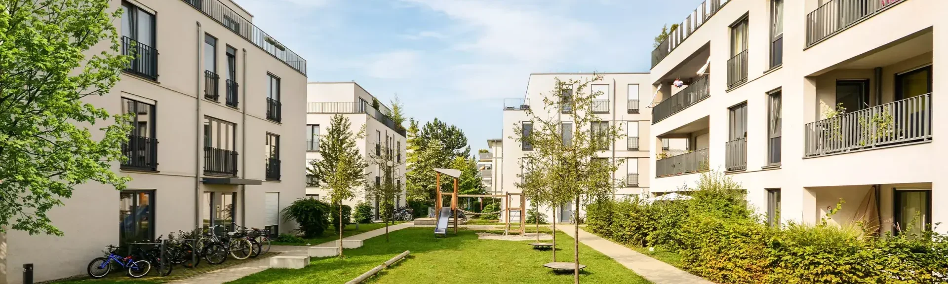 Innenhof in einer Wohngegend Blick in den Innenhof mit Mehrfamilienhäusern und Grünfläche mit Bäumen und kleinem Spielplatz